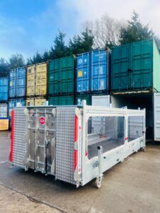 The International Export Packers Icon Auto Vault, a bespoke vehicle transport container, positioned in front of stacked shipping containers at the company's Newark facility. Designed to securely transport high-value vehicles, this unit was manufactured for a McLaren Solus GT.